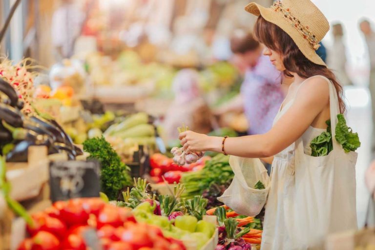 Woman is chooses fruits and vegetables at food market. Reusable eco bag for shopping. Zero waste concept.